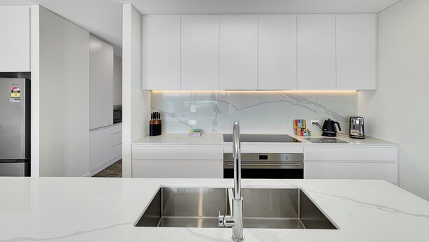 A modern kitchen with white cabinetry, a stainless steel sink, and a skylight above. - Coastal 3-Bed Retreat Near Batemans Bay (Batemans Bay)