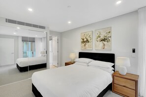 A modern hotel bedroom with a large bed, bedside tables with lamps, a mirror, and two floral paintings on the wall. - Coastal 3-Bed Retreat Near Batemans Bay (Batemans Bay)
