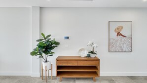 A minimalist room with a wooden console table, a potted plant, a wall-mounted thermostat, and a framed artwork. - Coastal 3-Bed Retreat Near Batemans Bay (Batemans Bay)