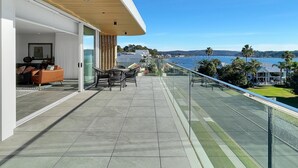 A balcony with a view of the sea, outdoor furniture, and a glass railing. - Coastal 3-Bed Retreat Near Batemans Bay (Batemans Bay)