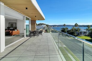 A balcony with a view of the sea, outdoor furniture, and a glass railing. - Coastal 3-Bed Retreat Near Batemans Bay (Batemans Bay)