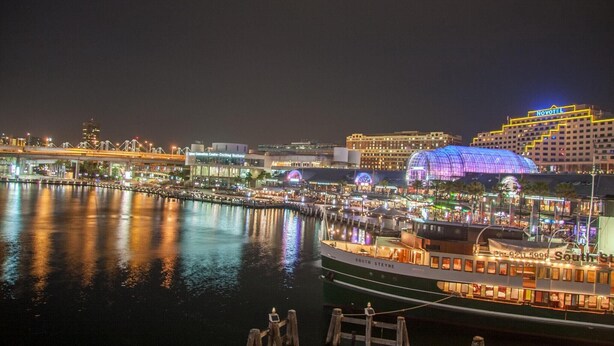 Un hotel sul lungomare con una grande cupola illuminata, una barca ormeggiata e un ponte sullo sfondo.