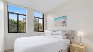 Una camera da letto con un letto, un comodino, una lampada e un quadro appeso al muro.