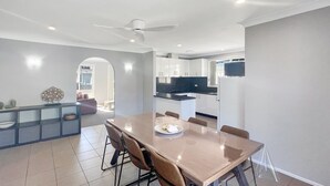 Ein moderner Essbereich mit großem Tisch, Stühlen und Deckenventilator.