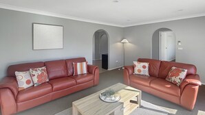 Ein modernes Wohnzimmer mit zwei Ledersofas, einem Couchtisch und einem Gemälde an der Wand.