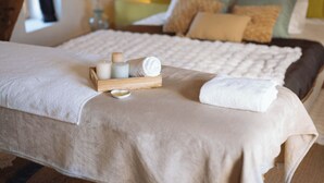 A bed with a white bedspread, a wooden tray with candles, and a rolled towel. - L'Atelier Vacation Rental (Wierre-Effroy)