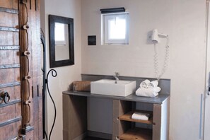 A bathroom with a wooden door, a white sink, a towel rack, and a mirror.