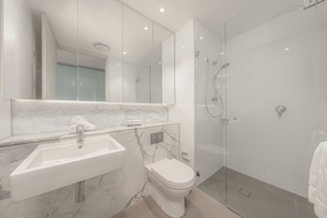 A modern bathroom with a marble sink, a toilet, and a glass-enclosed shower. - Cozy 2B2B Apartment In Burwood (Burwood)