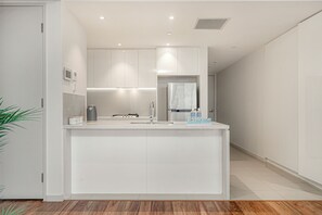 A modern kitchen with white cabinetry, a stainless steel refrigerator, and a built-in oven. - Cozy 2B2B Apartment In Burwood (Burwood)