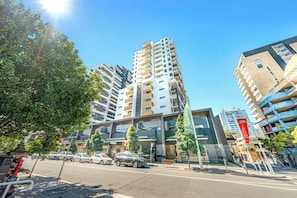 A multi-story building with a modern architectural design, featuring balconies and a central atrium. - Cozy 2B2B Apartment In Burwood (Burwood)