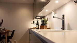 Eine moderne Küche mit weißer Arbeitsplatte, einem Spülbecken und einem Essbereich mit Tisch und Stühlen.