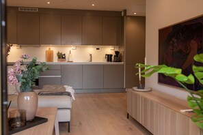 Una cuina moderna amb una illa central, zona de menjador amb una banqueta i un quadre a la paret.
