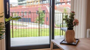 A room with a sliding glass door to an outdoor area, a potted plant, and a vase with flowers on a tray.