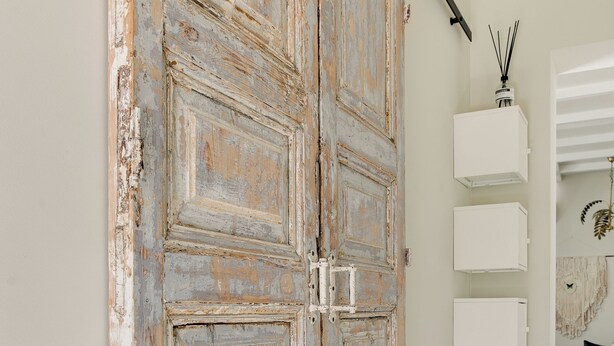 A rustic wooden door with a sliding mechanism, white wall-mounted cabinets, and a woven rug on the floor. - Brand new 2-bedroom cottage in centre of Zandvoort 500m to the beach (Zandvoort)