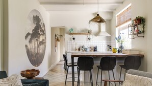 A modern kitchen with a central island, black bar stools, and a hanging light fixture. - Brand new 2-bedroom cottage in centre of Zandvoort 500m to the beach (Zandvoort)