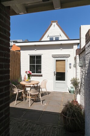 A white house with a door marked '9A,' a window, and a small patio with a table and chairs.