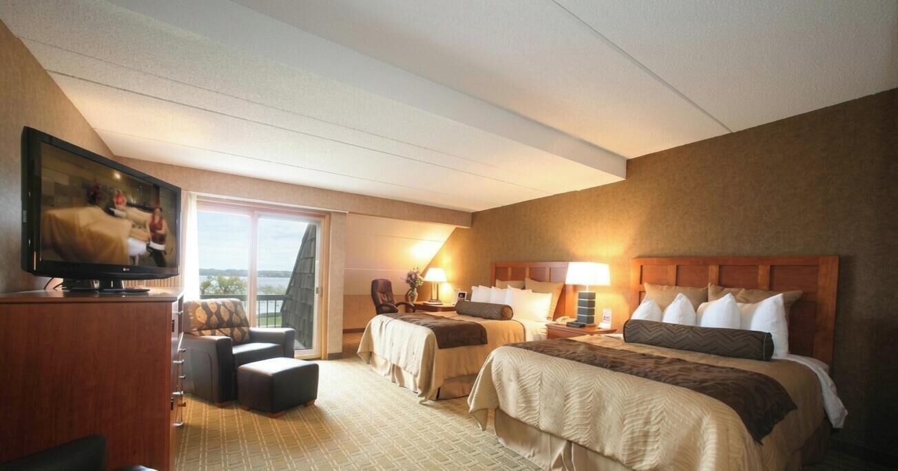 A hotel room with two beds, a television, a sofa, a chair, and a balcony with a view.. Luxury 4-Bedroom Alexandria Townhome, Lake Darling