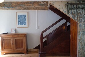 Eine Holztreppe mit Handlauf, ein gerahmtes Bild an der Wand und ein Holzkabinett mit Schubladen.