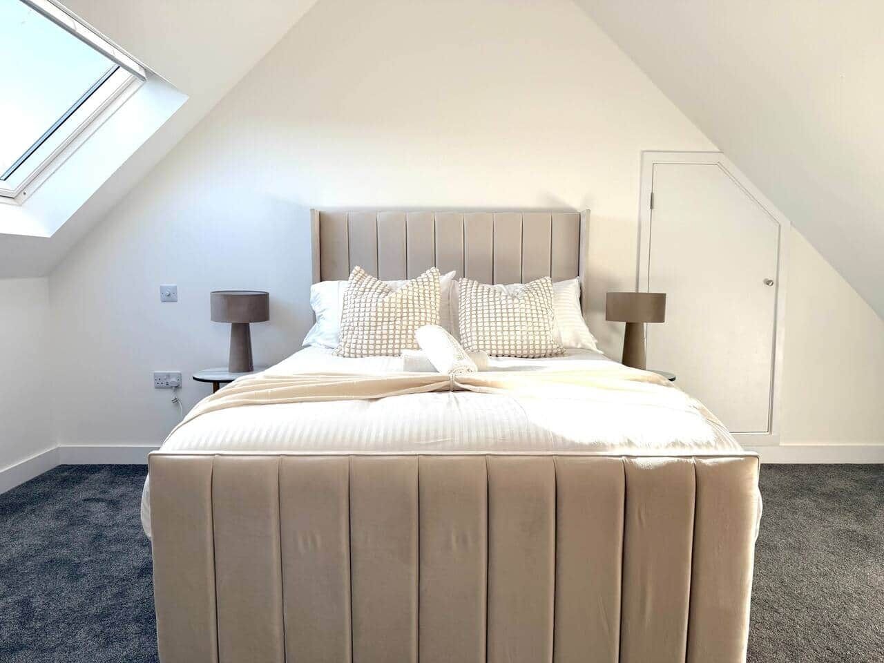 Une chambre à coucher avec un lit, deux tables de chevet, une fenêtre et une porte.