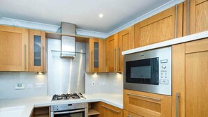 A modern kitchen with wooden cabinets, stainless steel appliances, and a white countertop. - Central 5-Bed, 2 En-Suites - Sleeps 12 - Parking (Cheltenham)
