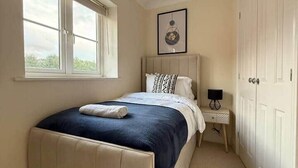 A bedroom with a bed, a window, a bedside table, and a wardrobe. - Central 5-Bed, 2 En-Suites - Sleeps 12 - Parking (Cheltenham)