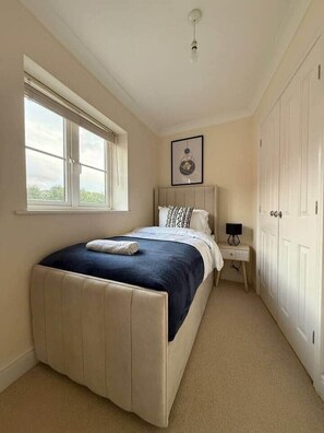A bedroom with a bed, a window, a bedside table, and a wardrobe. - Spacious 5bed in Cheltenham Town (Cheltenham)