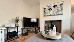 Una sala de estar moderna con una televisión de pantalla plana, una chimenea, un sofá y una bandeja con velas y un florero.