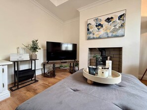 A modern living room with a flat-screen TV, a fireplace, a sofa, and a tray with candles and a vase. - Beautiful Modern Central Home (Cheltenham)