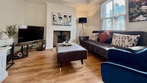 Una sala de estar con televisión de pantalla plana, chimenea, sofá y mesa de centro.