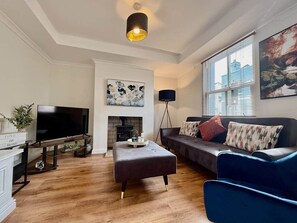 A living room with a flat-screen TV, a fireplace, a sofa, and a coffee table. - Beautiful Modern Central Home (Cheltenham)