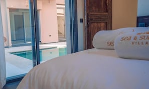 Habitación de hotel con una cama, una puerta de madera y vistas a una piscina.