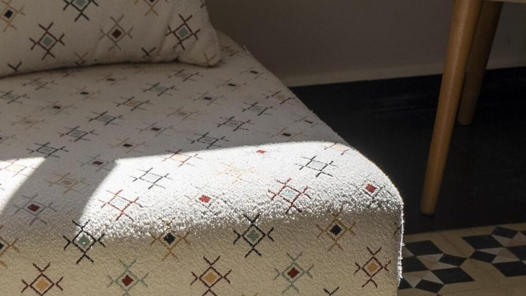 A bed with a patterned bedspread and a pillow.