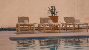 A poolside area with lounge chairs and a potted plant. - sea and sunset boutique villa (Taghazout)