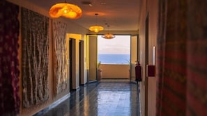 A hallway with a view of the sea, a fire extinguisher, and a door leading to a balcony.