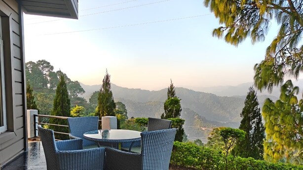 Une terrasse extérieure aménagée avec des meubles en osier et offrant une vue sur les montagnes lointaines.