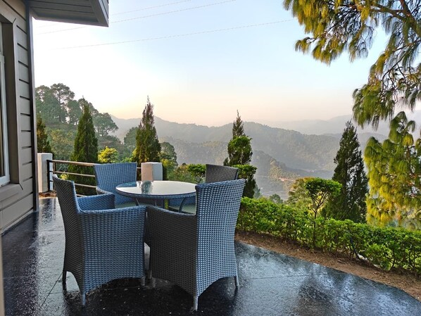 An outdoor patio with wicker furniture and a view of distant mountains.