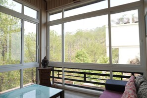 A room with large windows, a glass-top table, a sofa, and a Buddha statue.