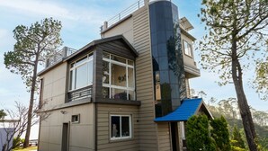 Une maison moderne à deux étages, dotée d’un balcon, d’un garage et d’un petit abri attenant.