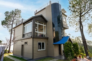 A modern two-story house with a balcony, a garage, and a small attached shed.