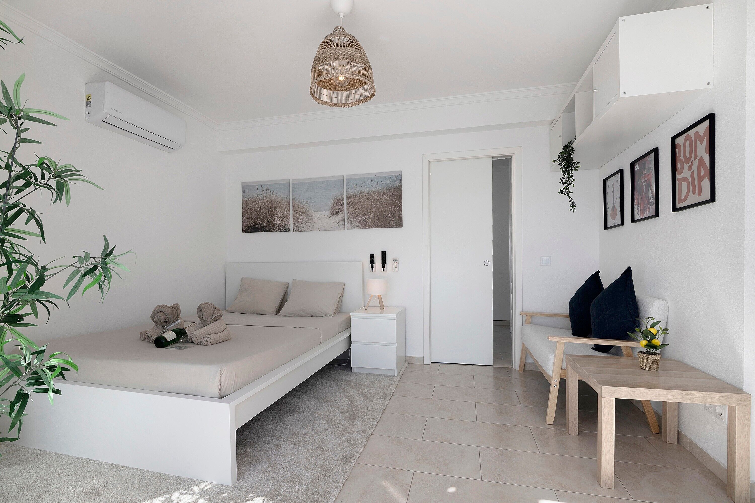 Une chambre à coucher au style minimaliste, avec un lit, une table de chevet et un luminaire suspendu.