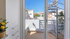 Ein Balkon mit Metalltreppe, einem Blumentopf und Blick auf Gebäude.