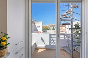 Un balcó amb una escala metàl·lica, una planta en test i vista d'edificis.