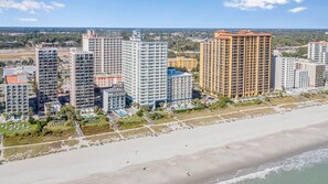 Een hotelcomplex aan de kust met meerdere hoge gebouwen, een strand en een zwembad.