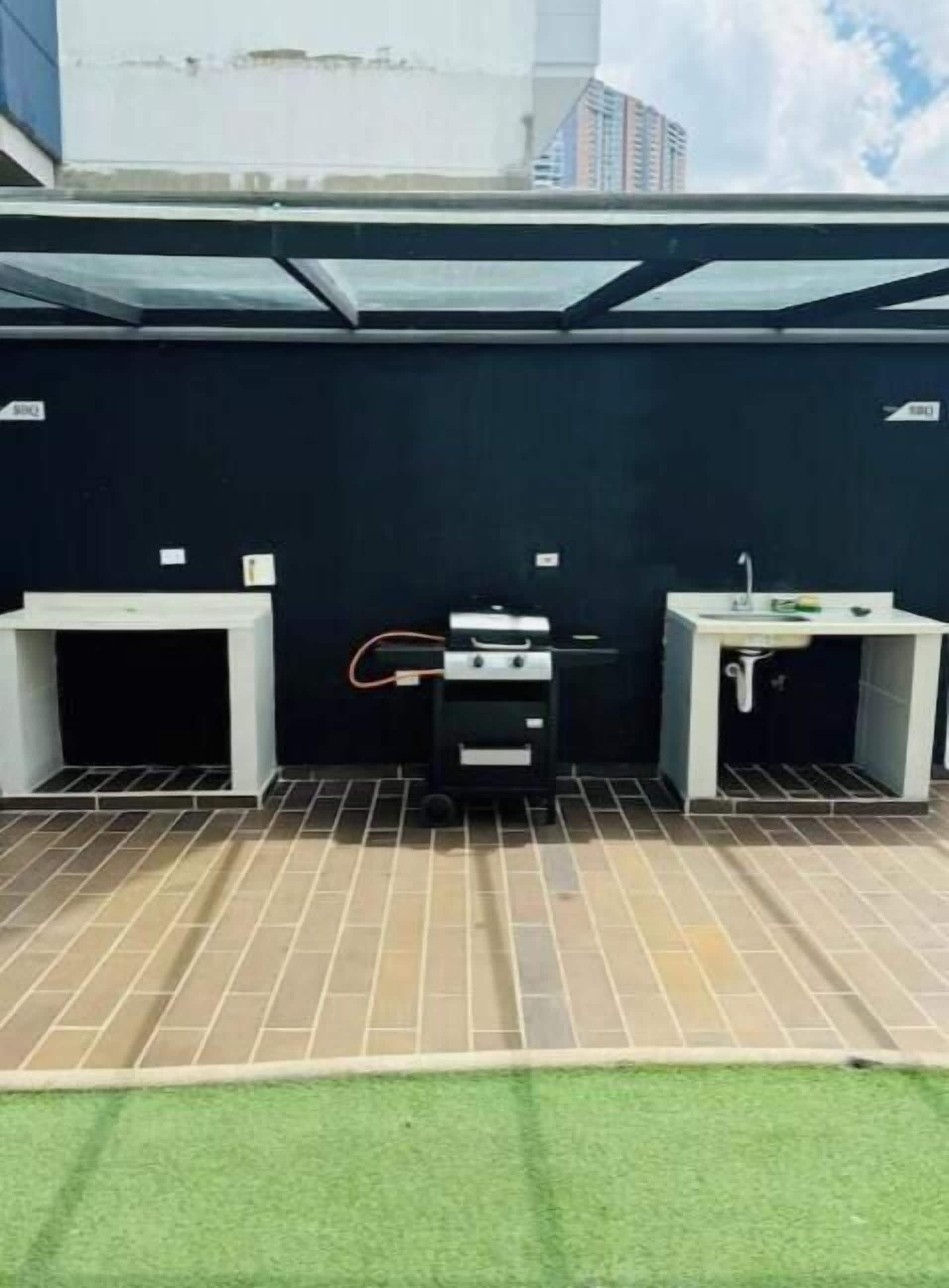 A rooftop area with a grill, a sink, and a small table.