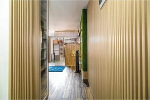 Un pasillo con listones de madera verticales, un tapete azul y una pared verde.