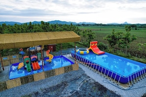 Ein Wasserpark mit Rutschen und Pool, umgeben von Feldern und Bergen.