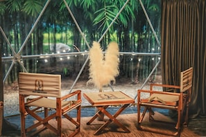 A room with a large window, two wooden chairs, a small table, and a decorative feather.