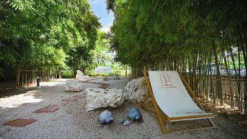 Un sendero bordeado de rocas y bambú, que lleva a una zona de estar con un cartel que dice 'REST THE BAMBOO'.