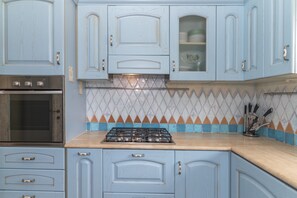 A kitchen with light blue cabinets, a gas stove, and a tiled backsplash.