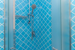 A bathroom with a blue tiled wall, a showerhead, and a faucet.